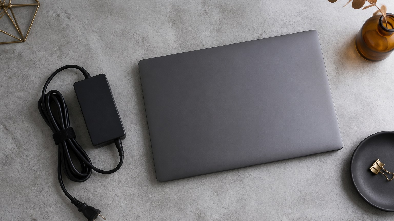 机に置いた電源アダプターとノートパソコンのイメージ