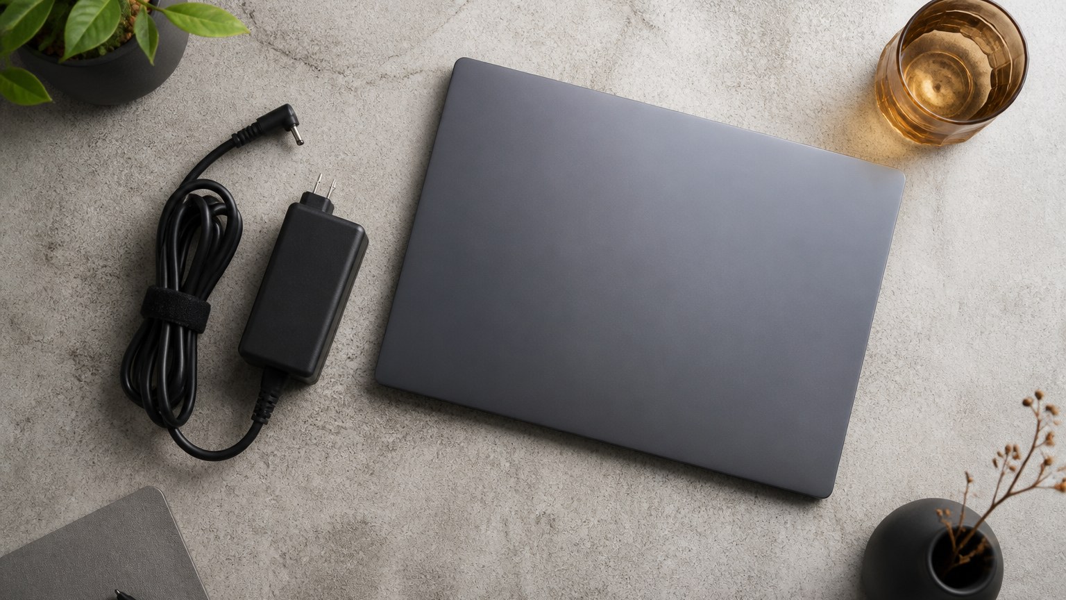 机に置いた電源アダプターとノートパソコンのイメージ